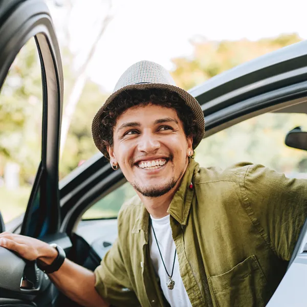 young man with a great smile getting out of his car