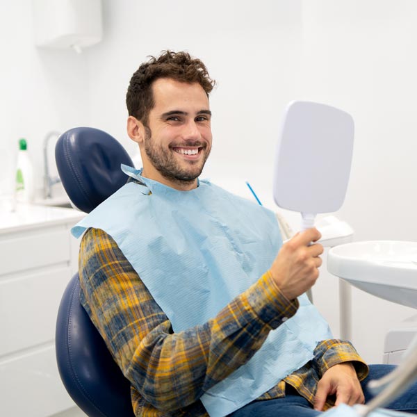 person smiling and looking at mirror in dental chair
