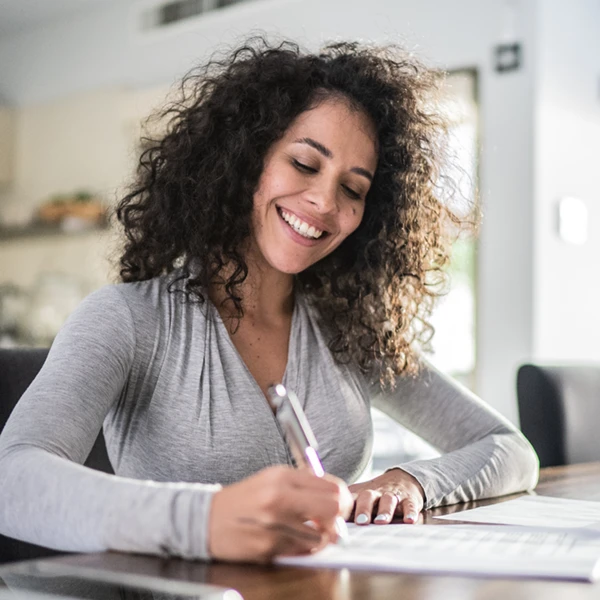 woman smiling and signing paperwork